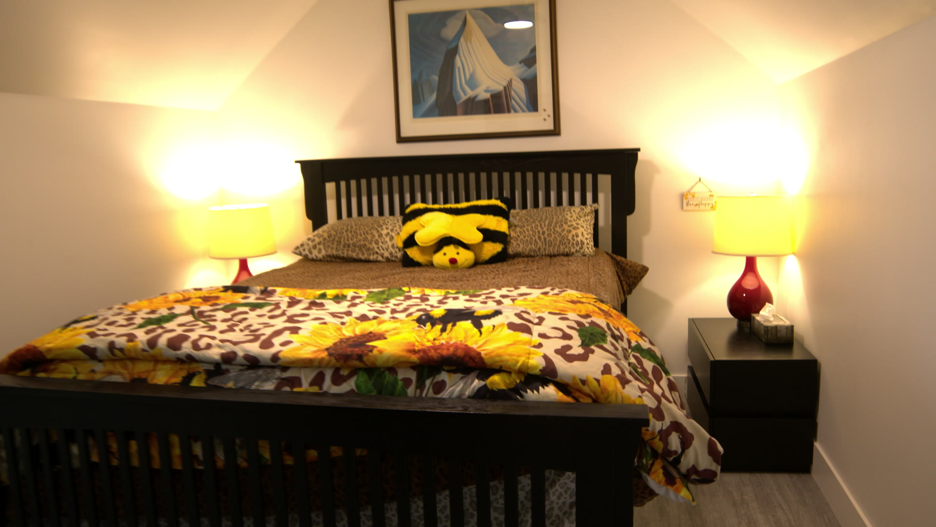 Bedroom with a dark wood bed, sunflower bedspread and two lamps