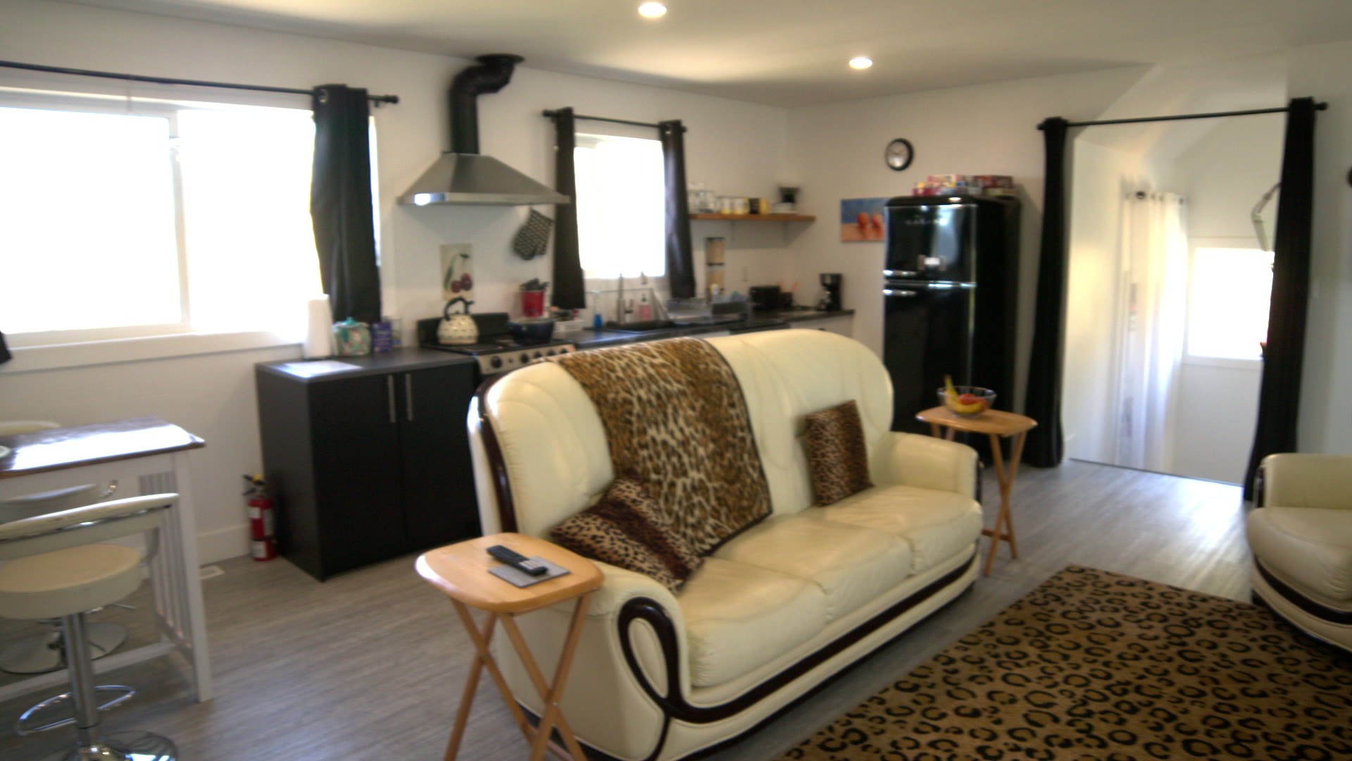 Suite Bee open-plan living room and kitchen: leather sofa, leopard-print rug, black retro fridge