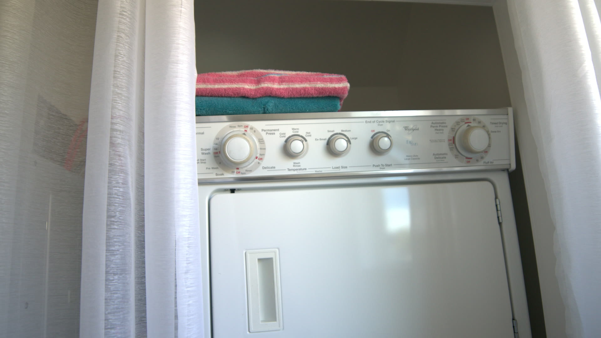 In-suite laundry: stacked washer and dryer with folded towels