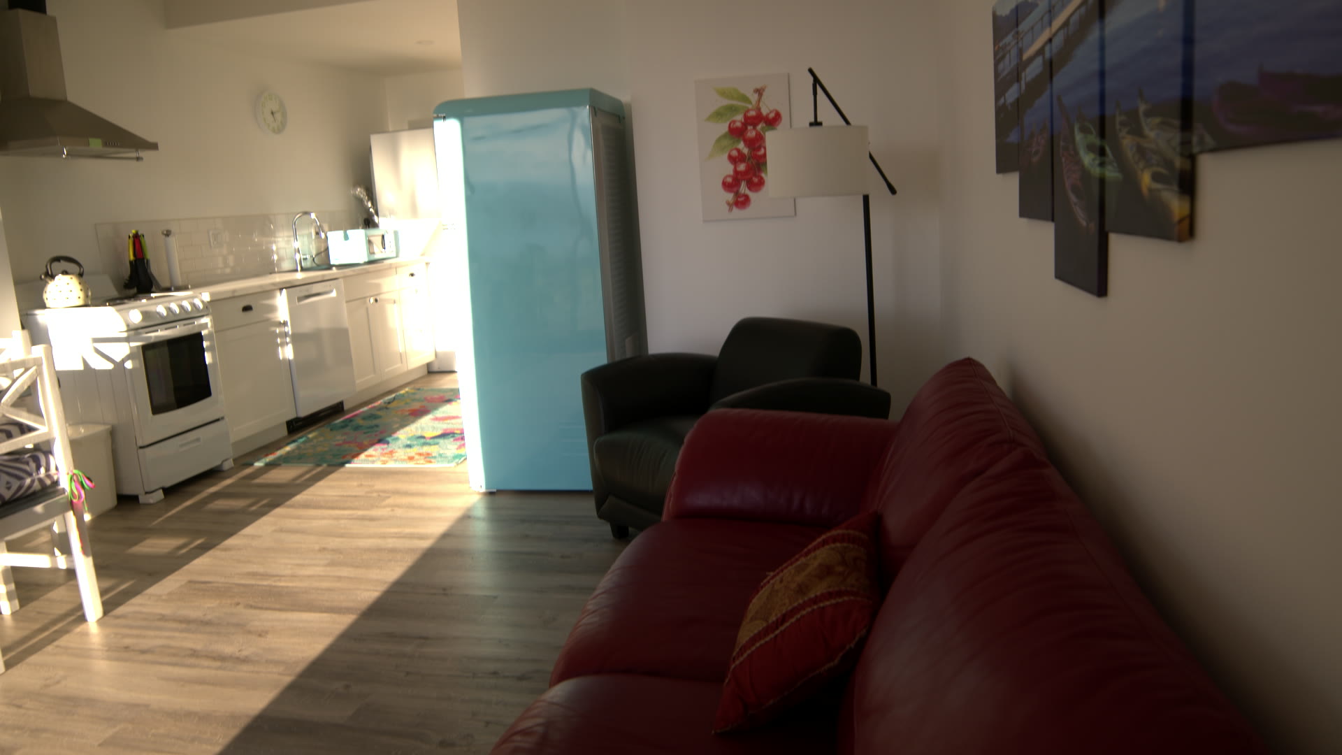 Suite Eh! living room: red leather sofa, teal retro fridge and the kitchen beyond